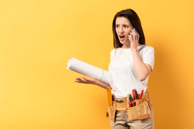 Şok olmuş becerikli kadın akıllı telefondan konuşuyor ve projeyi sarı arka planda tutuyor. 