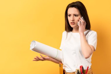 Şok olmuş becerikli kadın akıllı telefondan konuşuyor ve projeyi sarı arka planda tutuyor. 