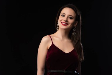 Siyah giyinmiş gülümseyen kadın kameraya bakıyor.