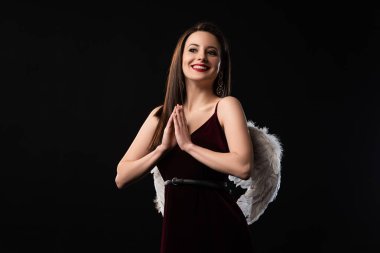 Kanatları olan gülümseyen bir kadın kara üzerinde dua eden elleri gösteriyor.