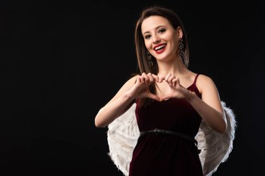 Kanatları olan gülümseyen kadın siyah üzerine izole edilmiş kalp hareketi sergiliyor.