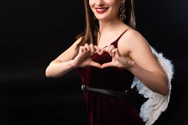 Kanatları olan gülümseyen bir kadın, siyah üzerine izole edilmiş kalp hareketi sergiliyor.