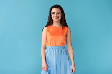 Gülümseyen ve çekici bir kadın mavi arka planda kameraya bakıyor. 