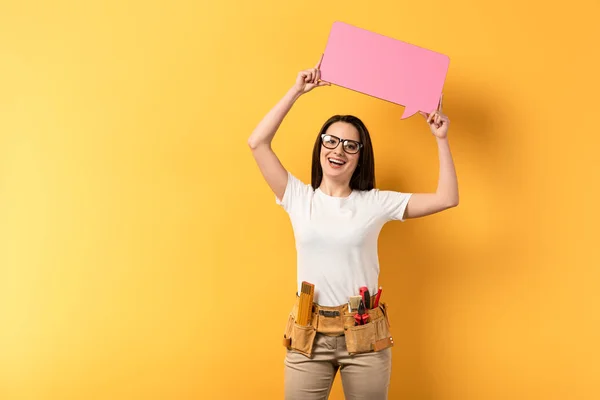 Smiling Repairwoman Holding Speech Bubble Looking Camera Yellow Background — Stock Photo, Image