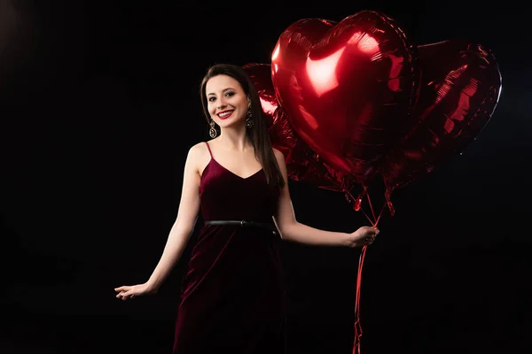 Χαμογελαστή Γυναίκα Φόρεμα Κρατώντας Μπαλόνια Σχήμα Καρδιάς Φεβρουαρίου Απομονωμένα Μαύρο — Φωτογραφία Αρχείου