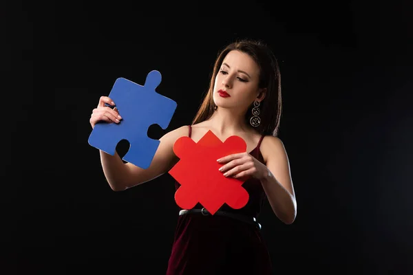 Nachdenkliche Frau Kleid Mit Puzzlefiguren Auf Schwarzem Hintergrund — Stockfoto