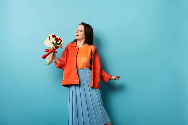 Schockierte Frau Jacke Mit Blumenstrauß Auf Blauem Hintergrund — Stockfoto