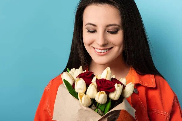 Mujer Sonriente Con Chaqueta Sosteniendo Ramo Sobre Fondo Azul — Foto de Stock