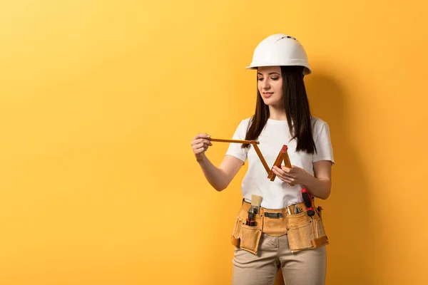 Sorrindo Handywoman Medidor Capacete Segurando Fundo Amarelo — Fotografia de Stock