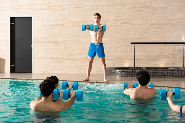 水中有氧运动中哑铃人与训练员一起锻炼的选择性焦点 — 图库照片