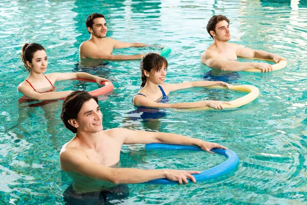 游泳健美操期间 一群年轻人在游泳池里拿着台面的高视角图像 — 图库照片