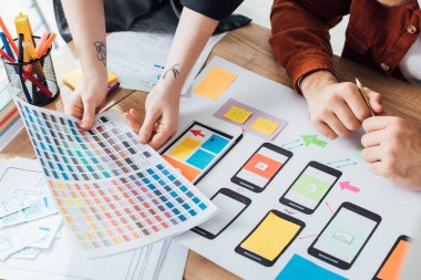 Renk paleti ve web sitesi çizimleri ile kullanıcı deneyimi tasarımı planlayan tasarımcıların kırpılmış görünümü