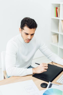 Web sitesi tasarımı ve tablo üzerindeki renk çemberinin şablonları yanında grafik tableti kullanan yakışıklı bir ux tasarımcı