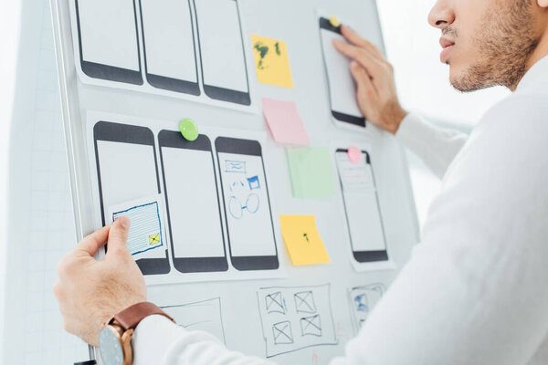 Cropped view of designer creative design of mobile website with templates on whiteboard in office 