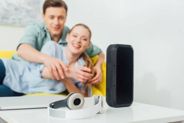 Kablosuz hoparlörlerin, kulaklıkların ve laptopun seçici odağı evdeki kanepenin yanındaki kahve masasının üzerinde.