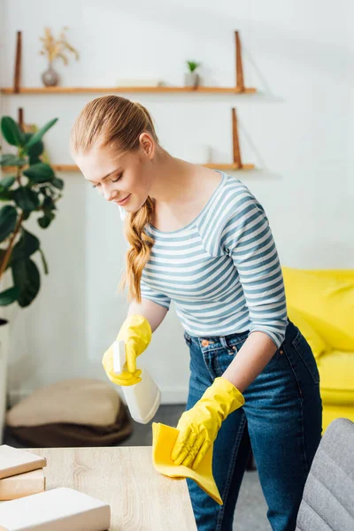 リビングでテーブルを掃除しながら ラグと洗剤を保持ゴム手袋の魅力的な女性 — ストック写真