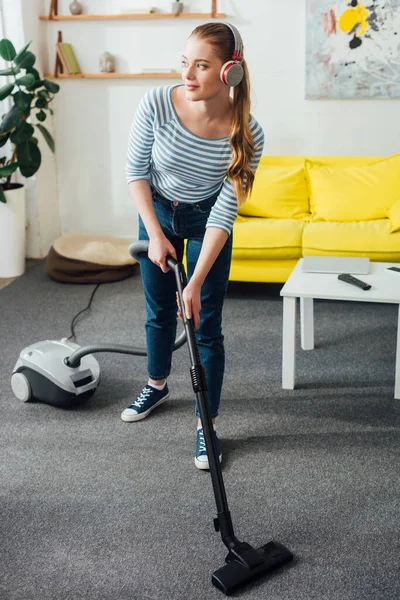 Gadis Cantik Mendengarkan Musik Headphone Sambil Membersihkan Karpet Dengan Vacuum — Stok Foto