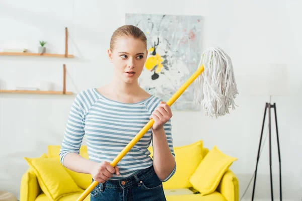 Attraktive Frau Hält Wischmopp Der Hand Und Schaut Wohnzimmer Weg — Stockfoto