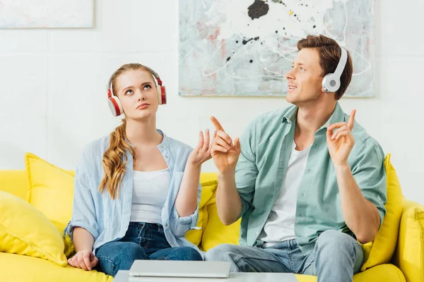 Pareja Joven Auriculares Escuchando Música Sofá Cerca Computadora Portátil Mesa —  Fotos de Stock