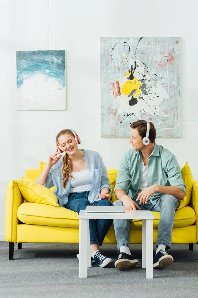 Young Couple Headphones Sitting Sofa Laptop Coffee Table — Stock Photo, Image