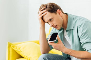 Sarı koltukta akıllı telefonla konuşan adamın hoparlör kullanışının yan görüntüsü 