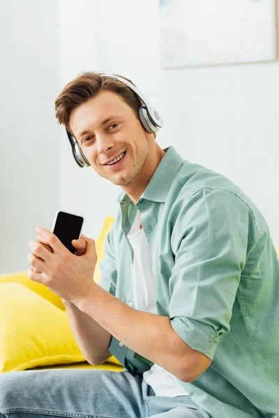 Side View Man Headphones Smiling Camera Holding Smartphone Couch — Stock Photo, Image
