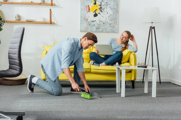 Man Schoonmaken Tapijt Met Primeur Bezem Buurt Glimlachende Vrouw Met — Stockfoto