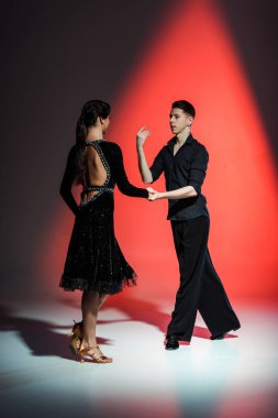 elegant young couple of ballroom dancers dancing in red light clipart