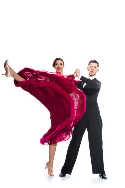 elegant young couple of ballroom dancers in red dress in suit dancing on white