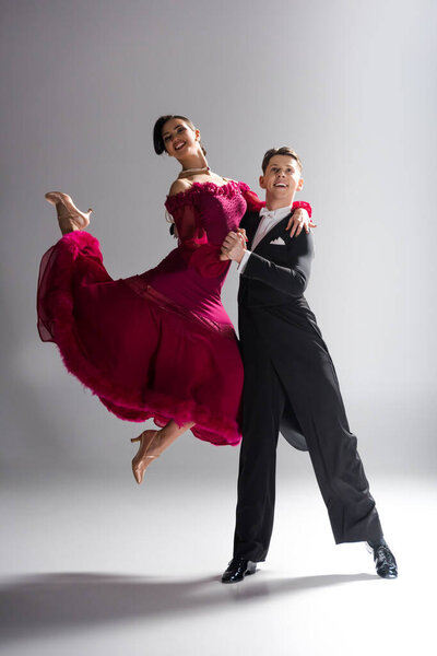 элегантная молодая пара танцовщиц в красном платье в костюме, танцующая на белом
