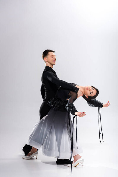 элегантная молодая пара танцовщиц в черном наряде танцует на белом
