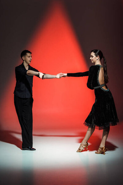 элегантная молодая пара танцоров, танцующих в красном свете
