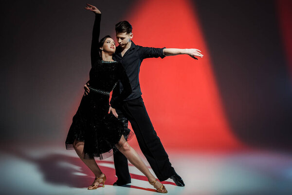 элегантная молодая пара танцоров, танцующих в красном свете
