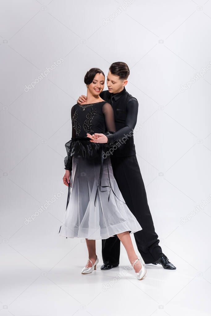 elegant young couple of ballroom dancers in black outfit dancing on white