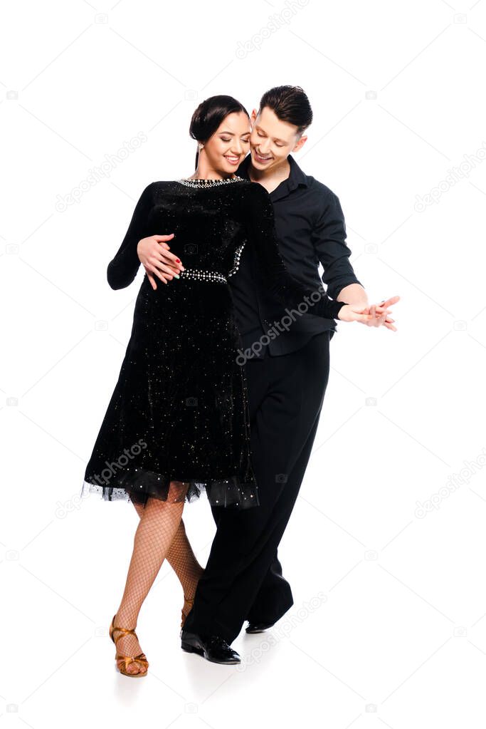 elegant young couple of ballroom dancers in black dress and suit dancing isolated on white