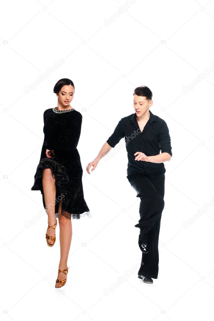 elegant young couple of ballroom dancers in black dress and suit dancing isolated on white