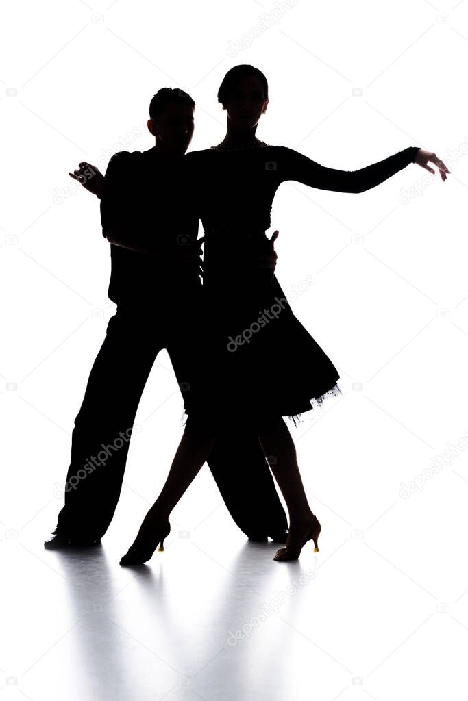silhouettes of elegant couple of ballroom dancers dancing on white