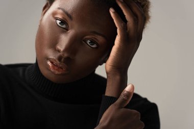 Siyahi balıkçı yaka kazaklı çekici Afro-Amerikan kadın, gri renkte izole edilmiş.
