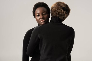 Siyahi balıkçı yakalı güzel Afro-Amerikan kadınları Gri boğazlılara sarılıyorlar