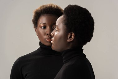 Siyah balıkçı yakalı Afro-Amerikan kadınlarının portresi gri renkte izole edilmiş.