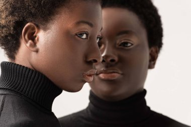 Siyah balıkçı yaka kazaklı Afro-Amerikan kızların portresi gri renkte izole edilmiş.
