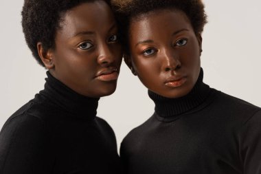 Siyah balıkçı yaka kazaklı güzel Afro-Amerikan kadınları gri renkte izole edilmiş.