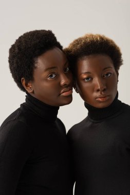 Siyahi balıkçı yaka kazaklı çekici Afro-Amerikan kadınları Gri üzerine izole edilmiş.
