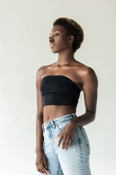 Beautiful african american girl in jeans and black top isolated on grey