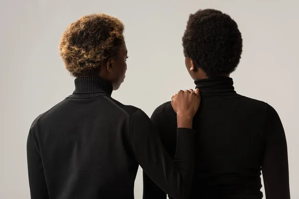 back view of african american women in black turtlenecks isolated on grey