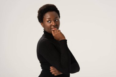 Düşünceli, gülümseyen, siyah balıkçı yakalı Afrikalı Amerikalı kadın.