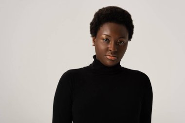 Siyahi balıkçı yaka kazaklı çekici Afro-Amerikan kadın, gri renkte izole edilmiş.