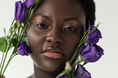 Mor östoma çiçekleri olan çekici Afro-Amerikalı kadın beyaza izole edilmiş.