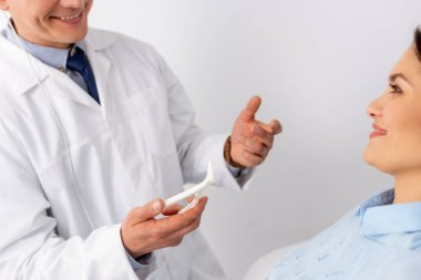 Çekici bir hastanın yanında burun spekulumu tutan gülümseyen doktor görüntüsü.