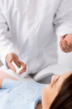 Hastaların yanında burun spekulumu tutan otolaringolojistin kırpılmış görüntüsü 